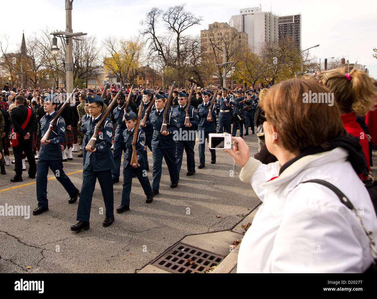 A woman photographs cadets during a Remembrance Day parade in Windsor, Ontario, Canada Stock Photo