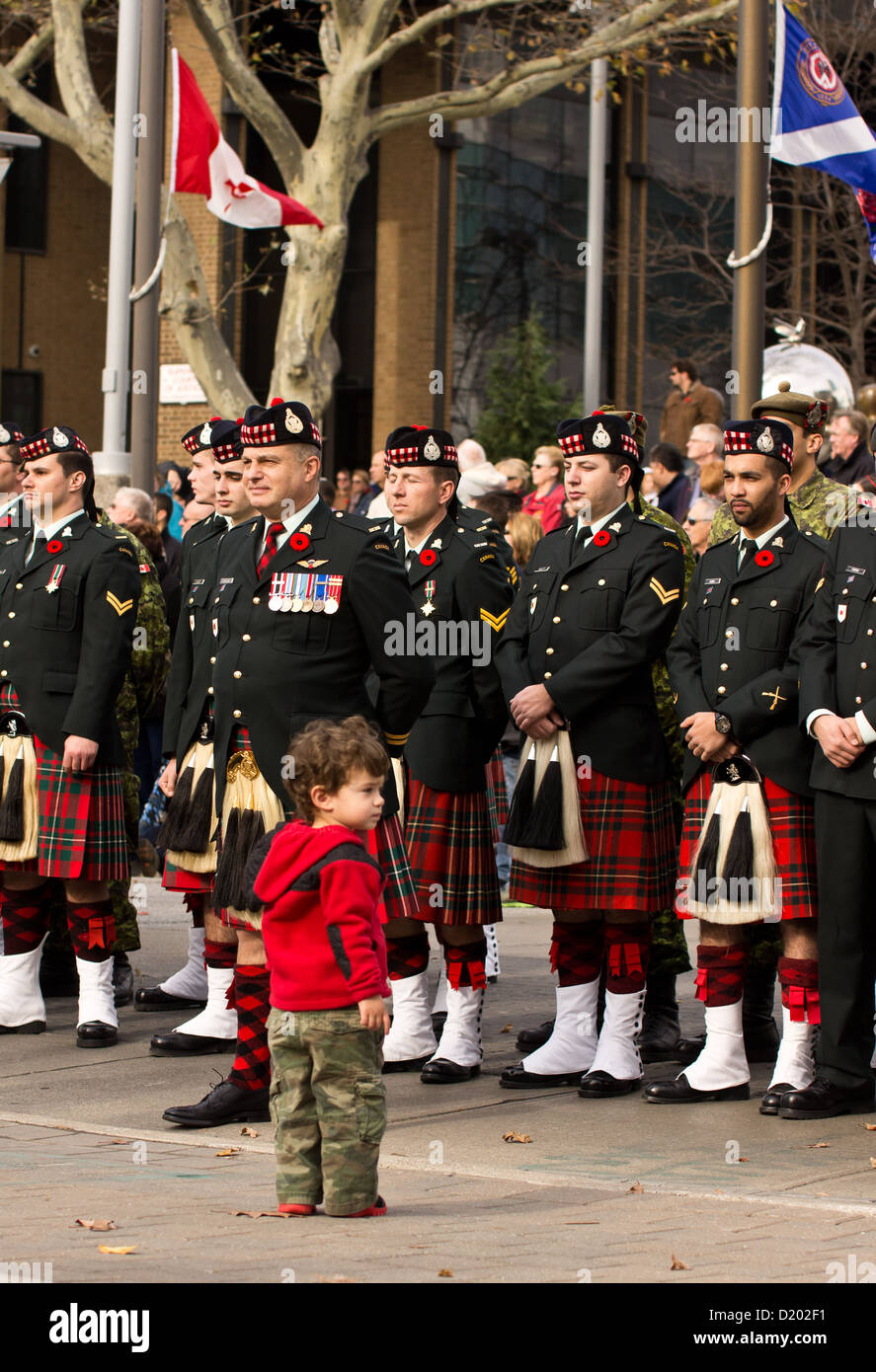 A child stands infront of uniformed soldiers at a Remembrance Day ceremony in Windsor, Ontario, Canada. Stock Photo
