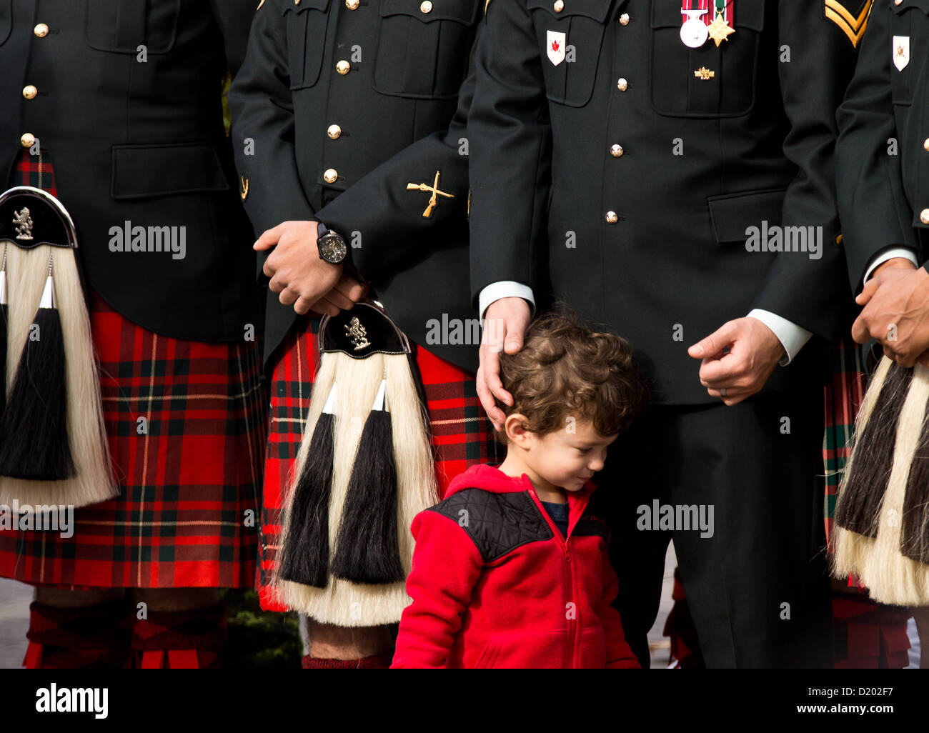A child with uniformed soldier's at a Remembrance Day ceremony. Stock Photo