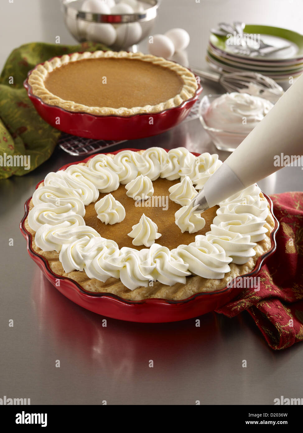 Piping a pumpkin pie in a kitchen setting with ingredients Stock Photo