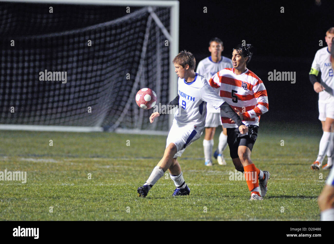 Soccer player turns as he attempts to control the ball off his chest during a high school soccer match. USA. Stock Photo