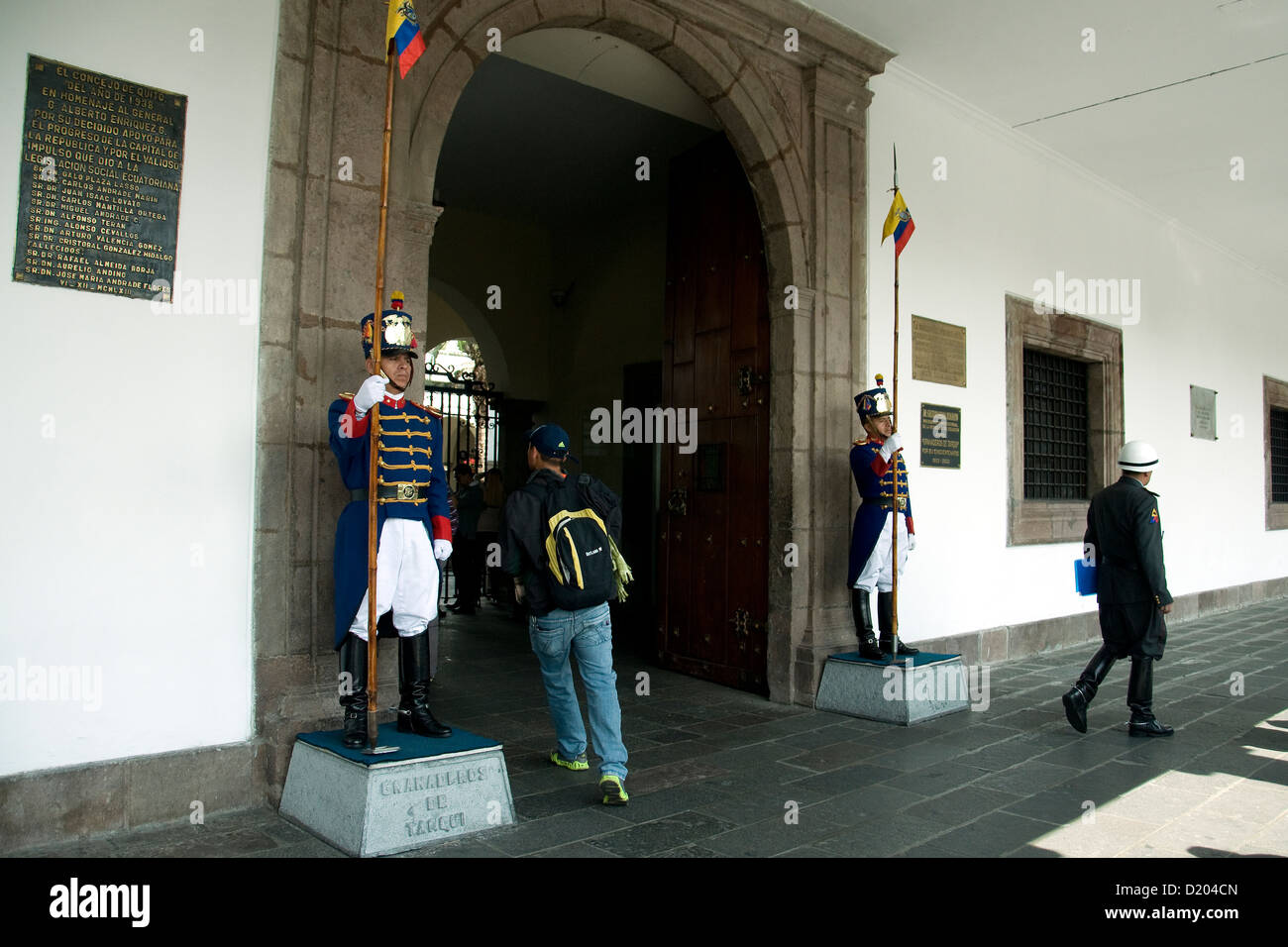 Smart Presidential guards nominally guard the entrance to the Presidential Palace in Quito, ignoring the backpacker heading in Stock Photo