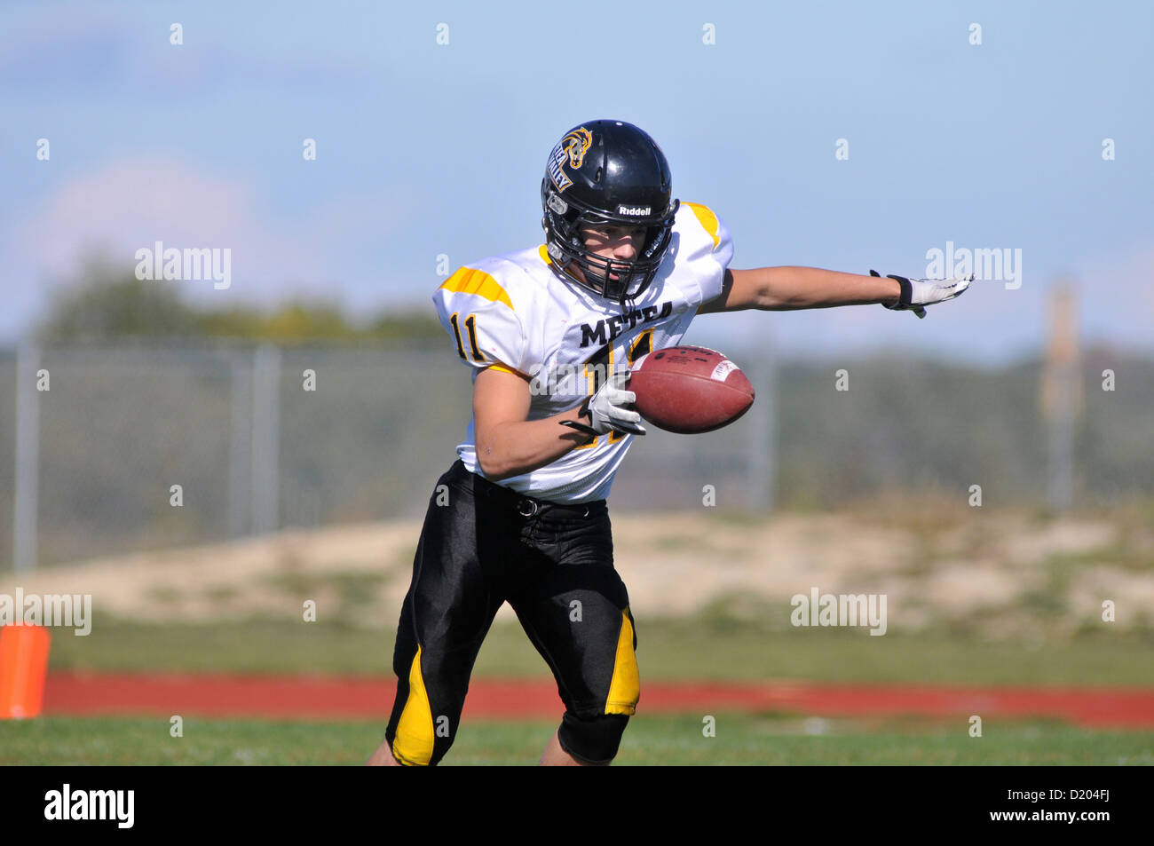 Football Punter releases the ball as he begins his stride to get off his kick during a high school game. USA. Stock Photo