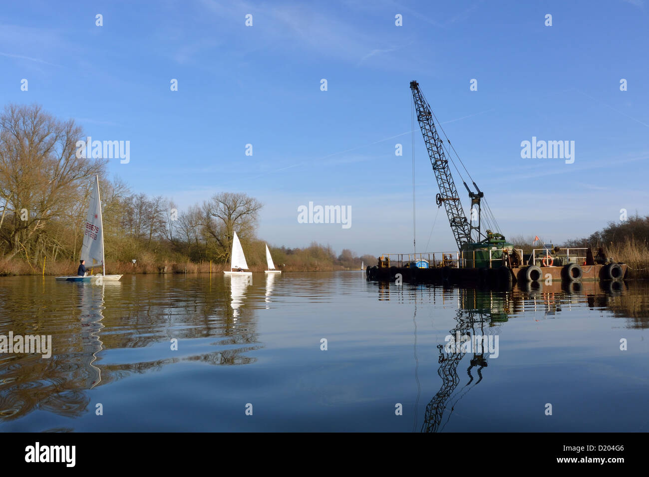 Laser sailing dinghies close to a dredger on the River Bure near
