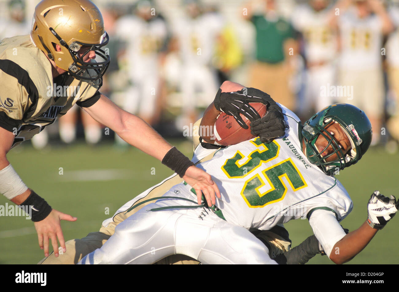 Football running back is driven backward after being tackled during a high school game. USA. Stock Photo