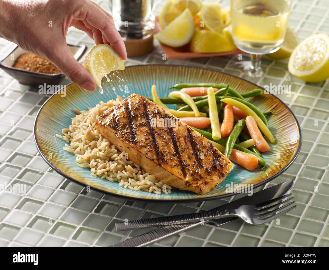 Blackened salmon with lemon squeeze over rice with vegetables Stock Photo