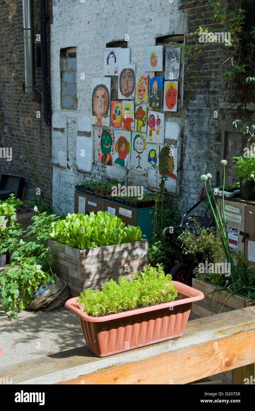 Vegetables growing in a variety of containers, with children's paintings in the background, Dalston Eastern Curve Garden Hackney Stock Photo