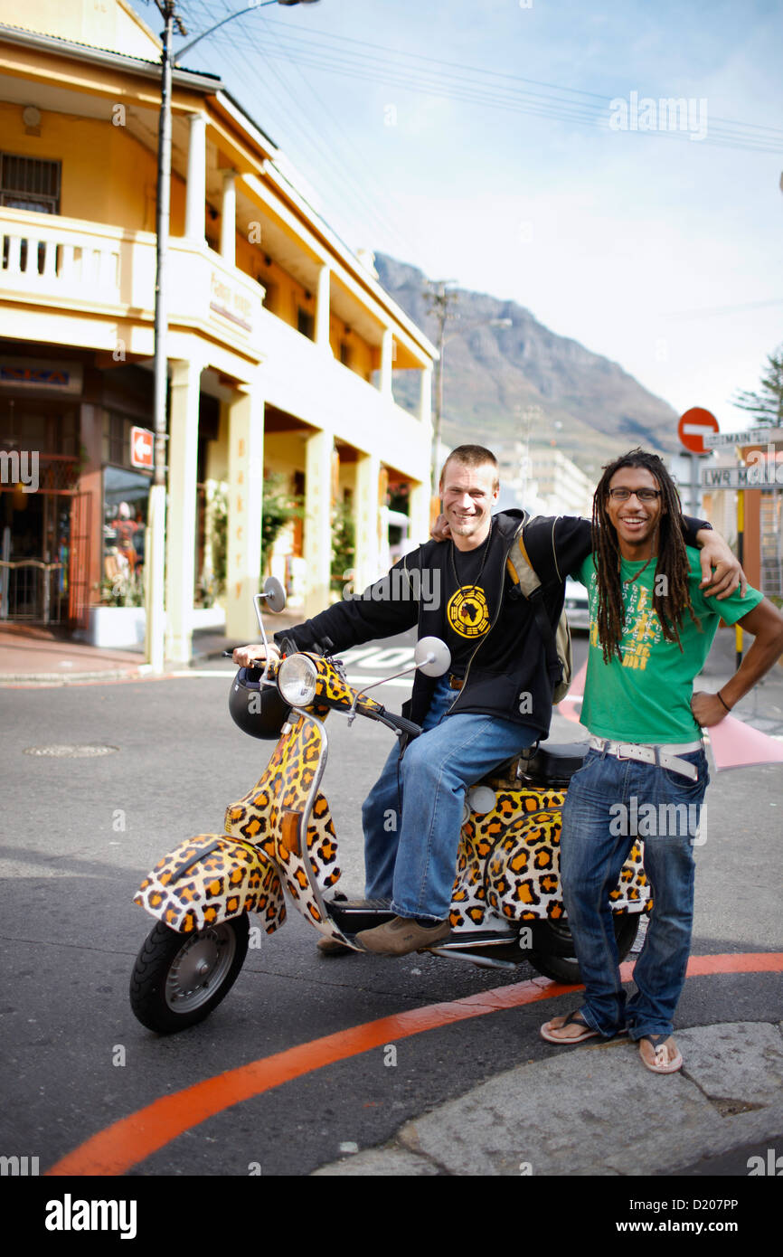 Two men on leopard print scooter cruising through Observatory, Southern