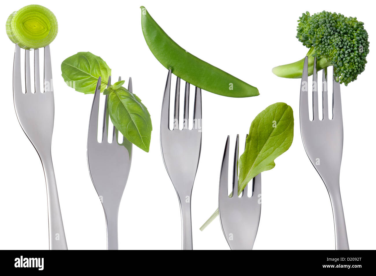 healthy raw green vegetables food on forks isolated against white: leek, basil, mange tout, lettuce, broccoli Stock Photo
