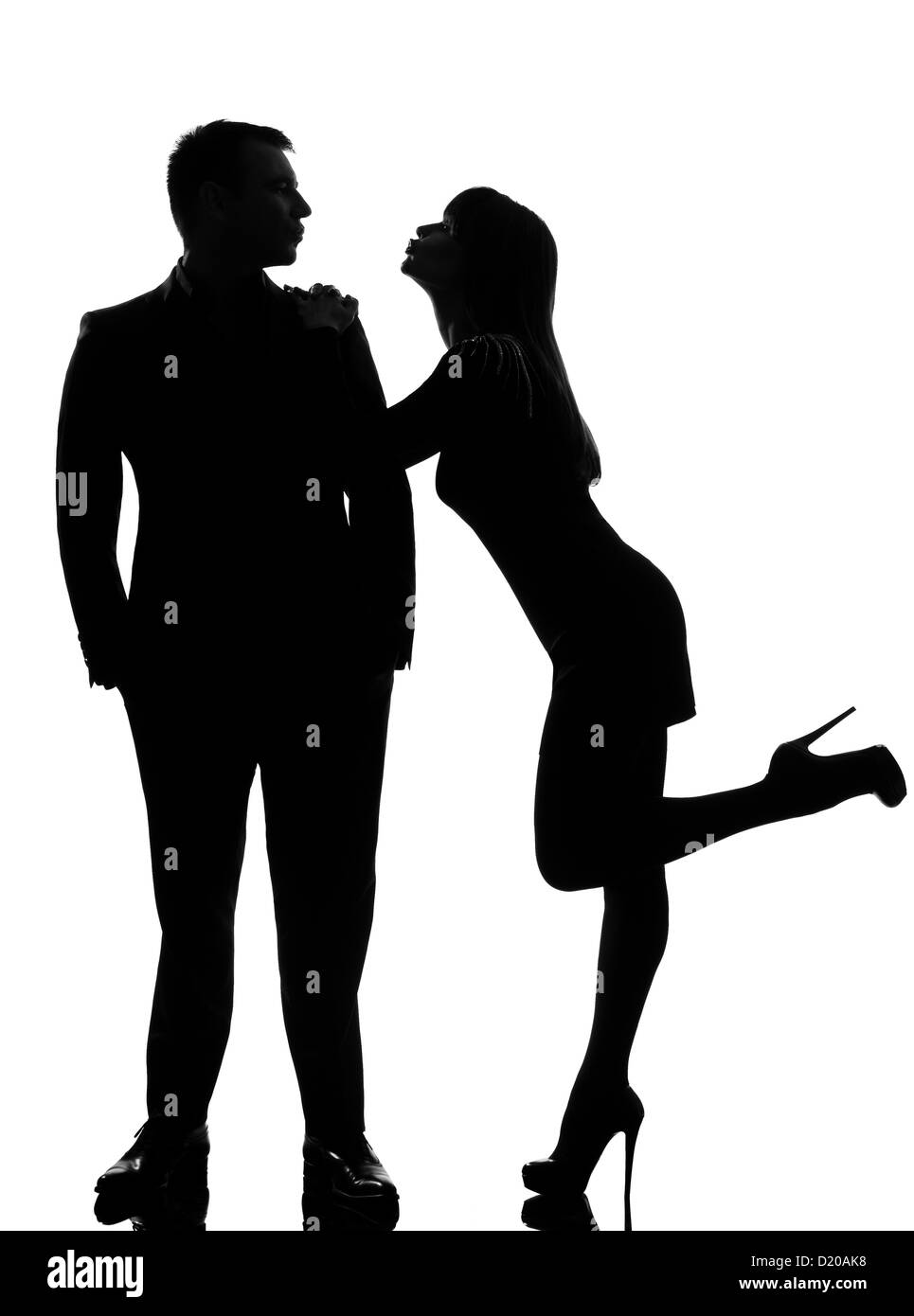 one caucasian couple lovers  woman wanting to kiss the man in studio silhouette isolated on white background Stock Photo