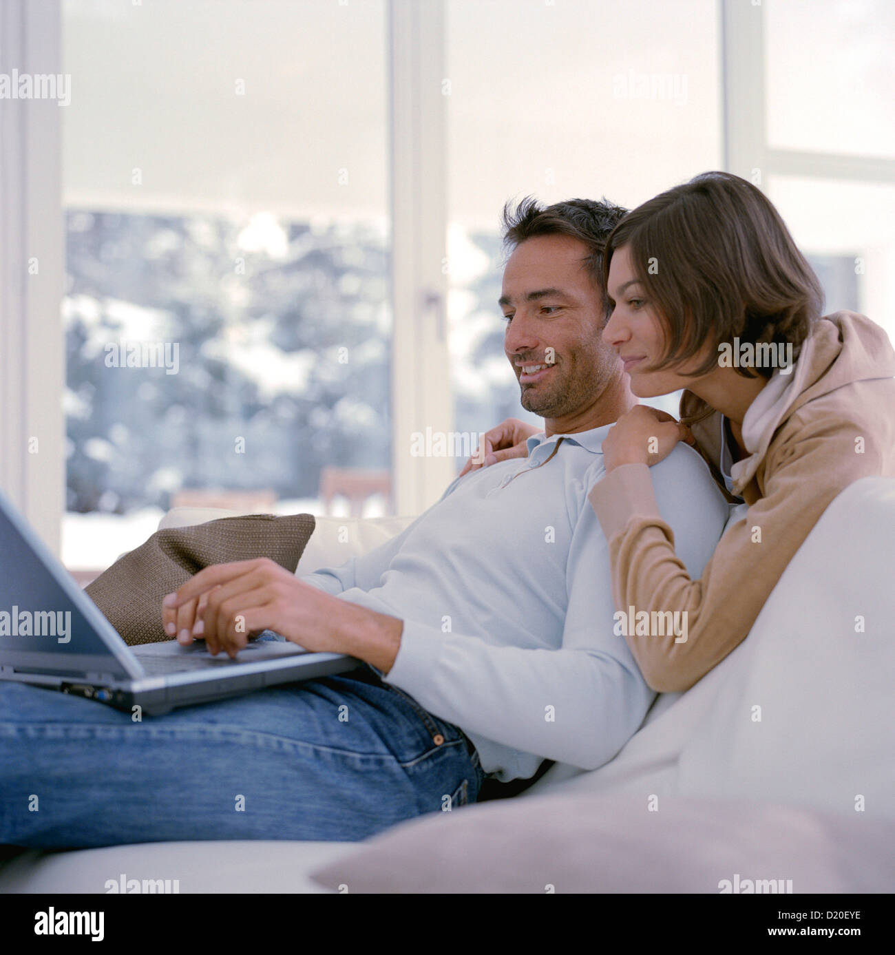 Happy mature couple using laptop together while sitting at home License free except ads and billboards Stock Photo