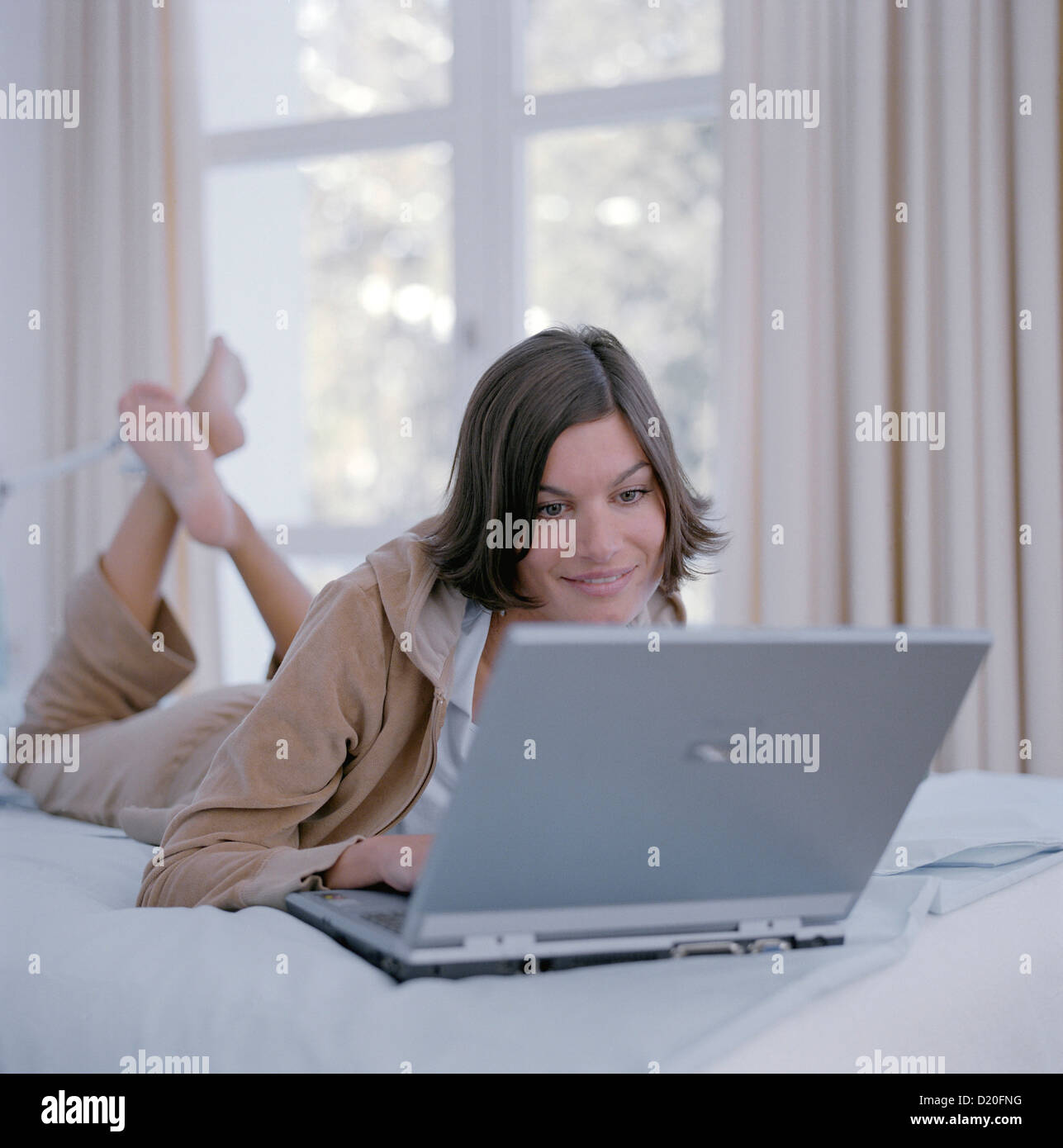 Closeup of a beautiful young woman lying on the couch with her laptop License free except ads and billboards Stock Photo