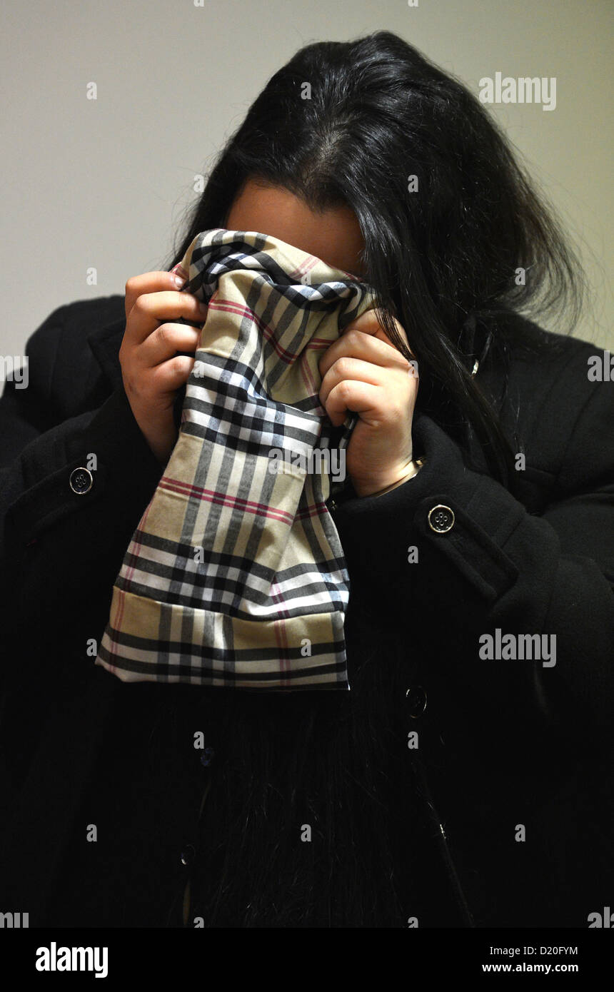 The 19-year-old defendant Sehrivan A. hides behind a scarf as he waits for the beginning of his trial at the Regional Court in Oldenburg, Germany, 09 January 2013. He is accused of attempted murder after stabbing his pregnant girlfriend in the stomach in summer 2012. Photo: CARMEN JASPERSEN Stock Photo