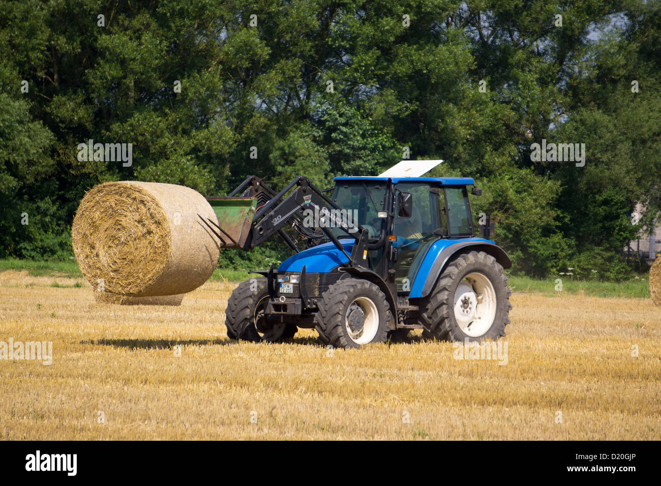 Farmer with a tractor loading a trailer with straw bales, Hanau, Hesse, Germany, Europe Stock Photo