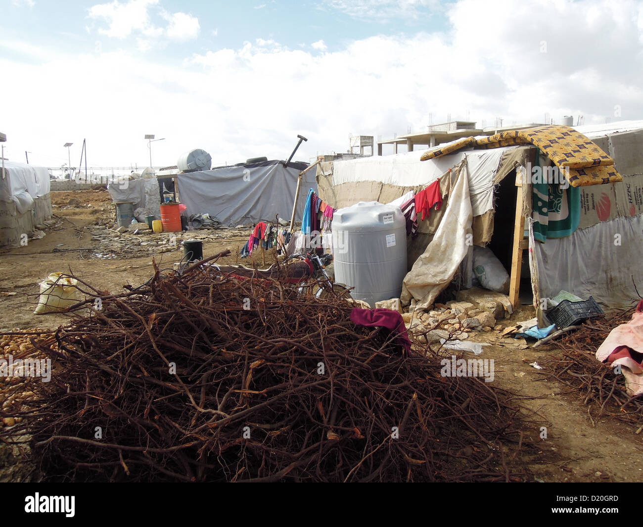 a camp for Syrian refugees near the town zahl in sout lebanon. the baracks are made from tarp over wooden frames. In front wood for heating the baracks. Stock Photo