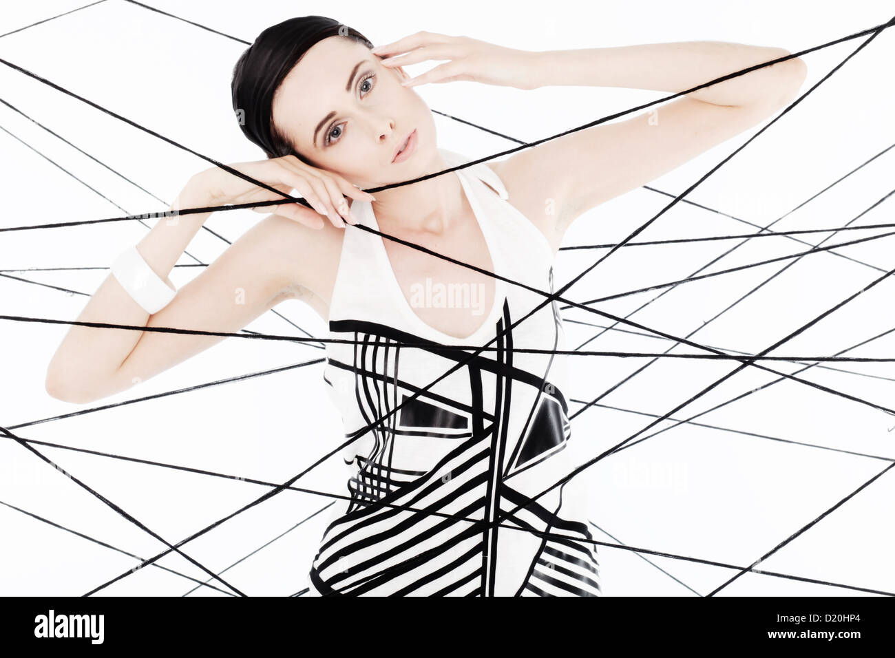 Woman, 24, dressed in the style of the 60s, standing between spanned threads, symbolic image network Stock Photo