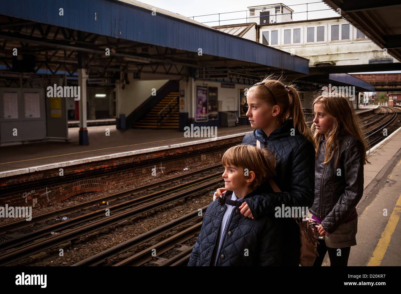 Three children waiting on the platform of an English railway station Stock Photo