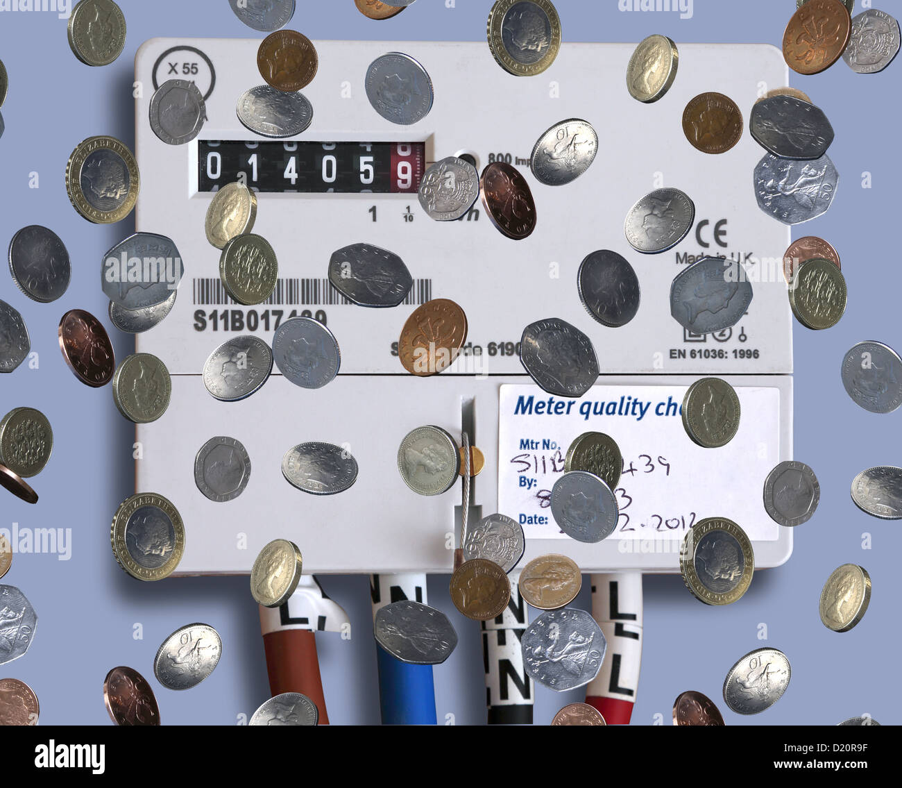 Coins falling next to a domestic electricity meter. Stock Photo