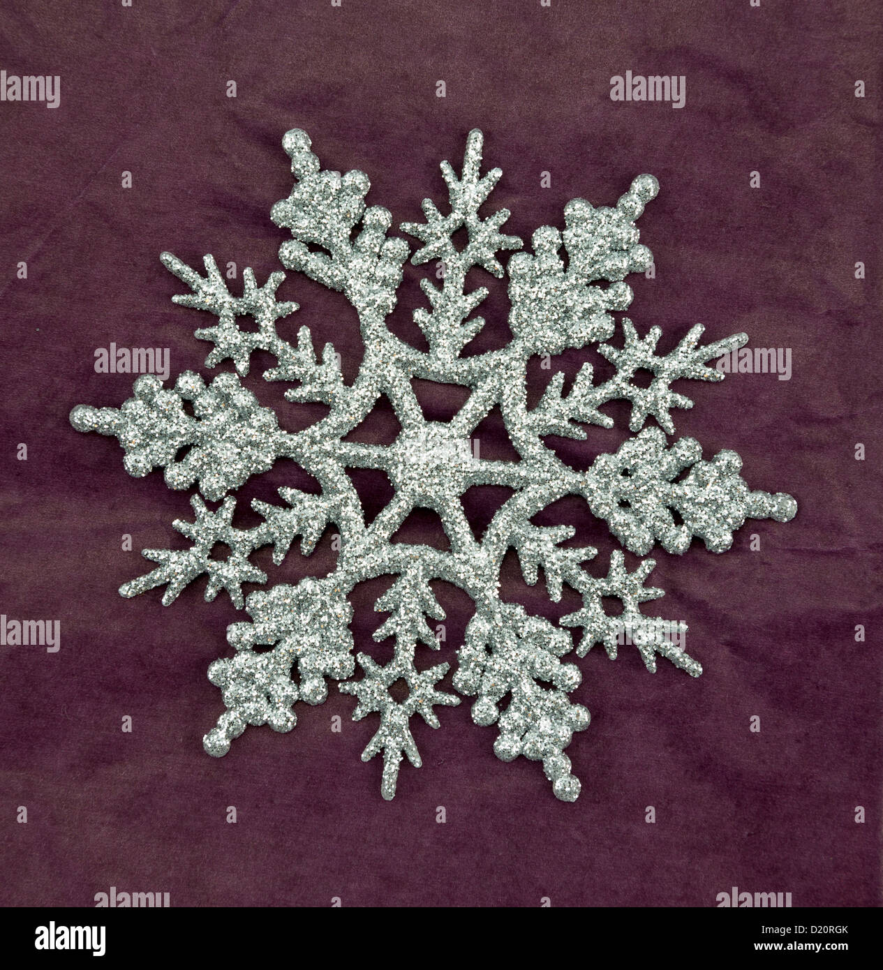 Silver glitter snowflake christmas ornament on a purple background. Stock Photo