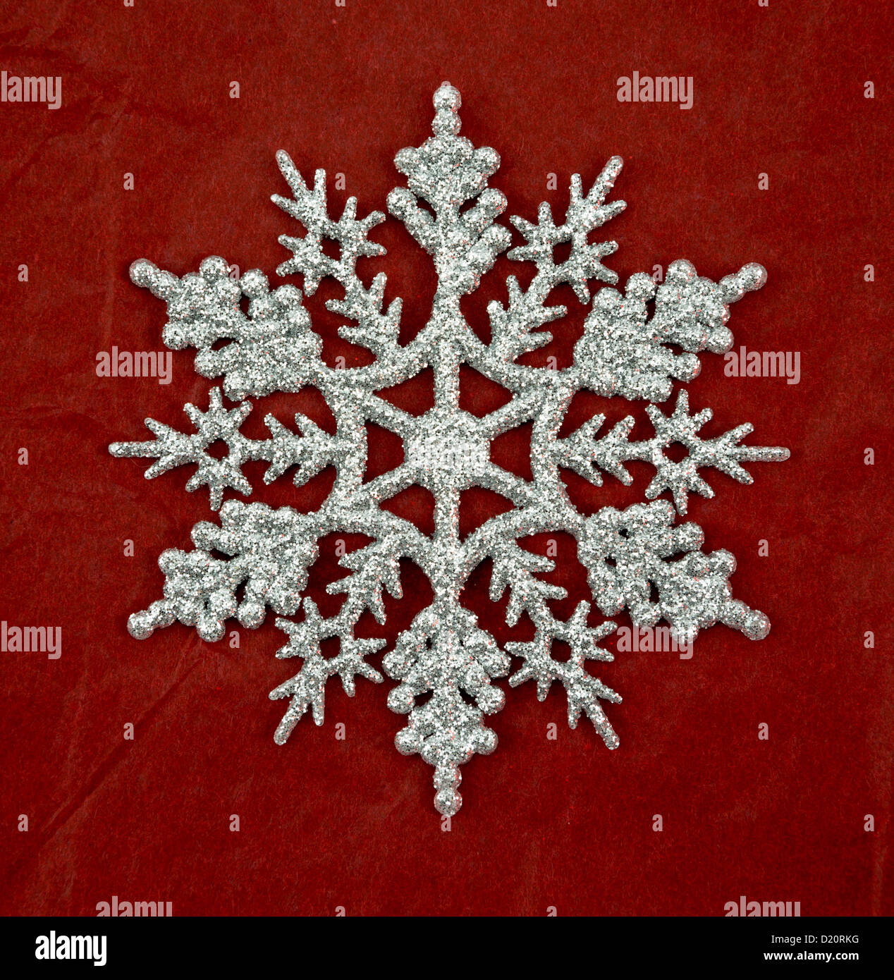 Silver glitter snowflake christmas ornament on a red background. Stock Photo
