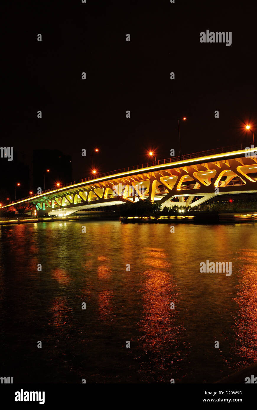Night photography of riverside vehicle bridge with beautiful lighting reflected upon the river water. Stock Photo