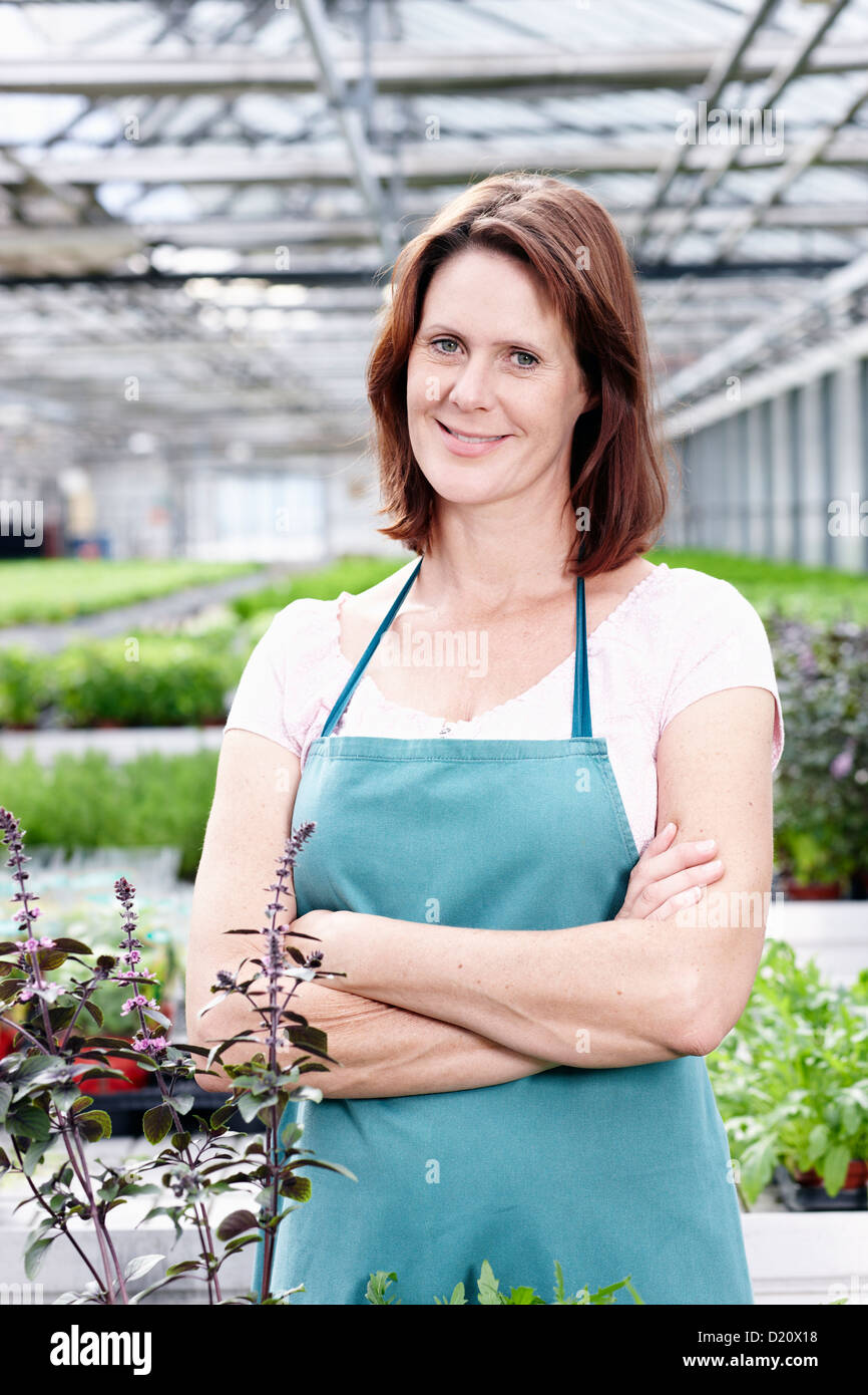 Germany, Bavaria, Munich, Mature woman in greenhouse, smiling, portrait