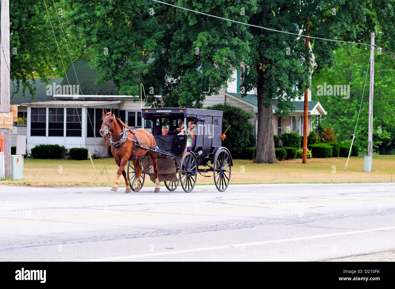 USA , Indiana, Middlebury, Elkhart County. Amish buggy full of family members is driven down the main street Stock Photo