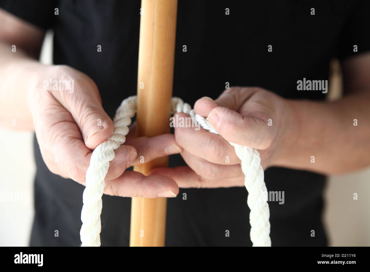 a man begins to tie a thick rope around a wooden pole Stock Photo Alamy