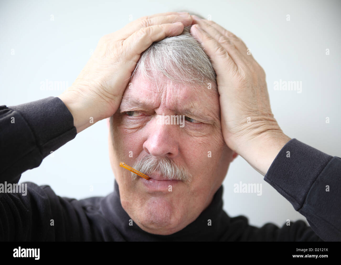 older man holds his head while taking temperature Stock Photo