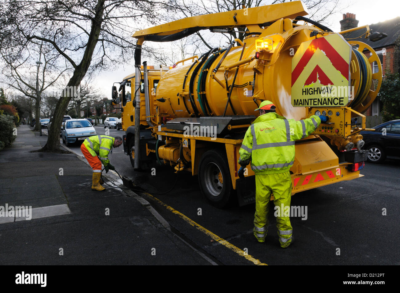 Workmen operating controls of pump on a drain cleaning lorry and flushing out drain Stock Photo