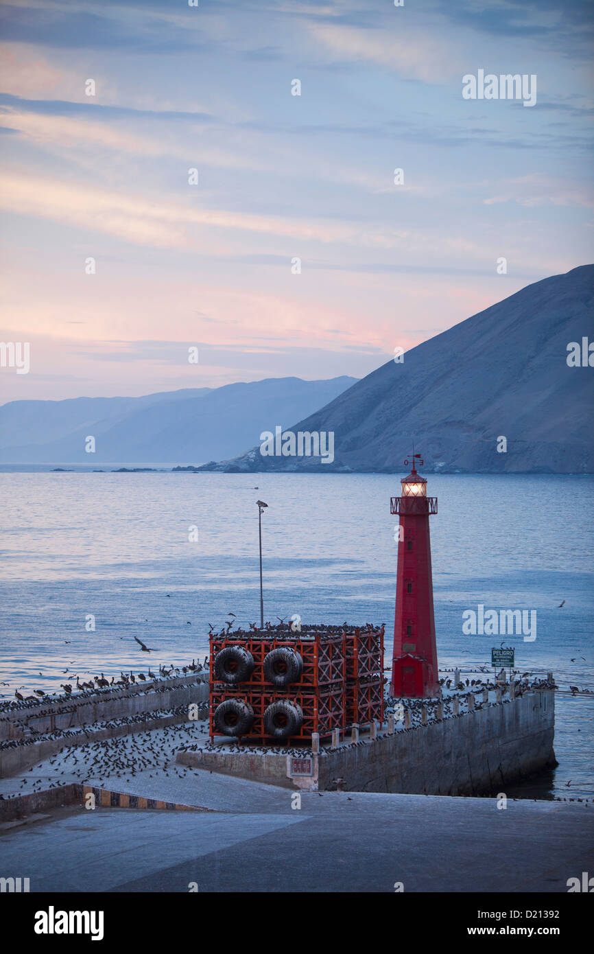Birds on pier and lighthouse at dusk, Iquique, Tarapaca, Chile, South America Stock Photo