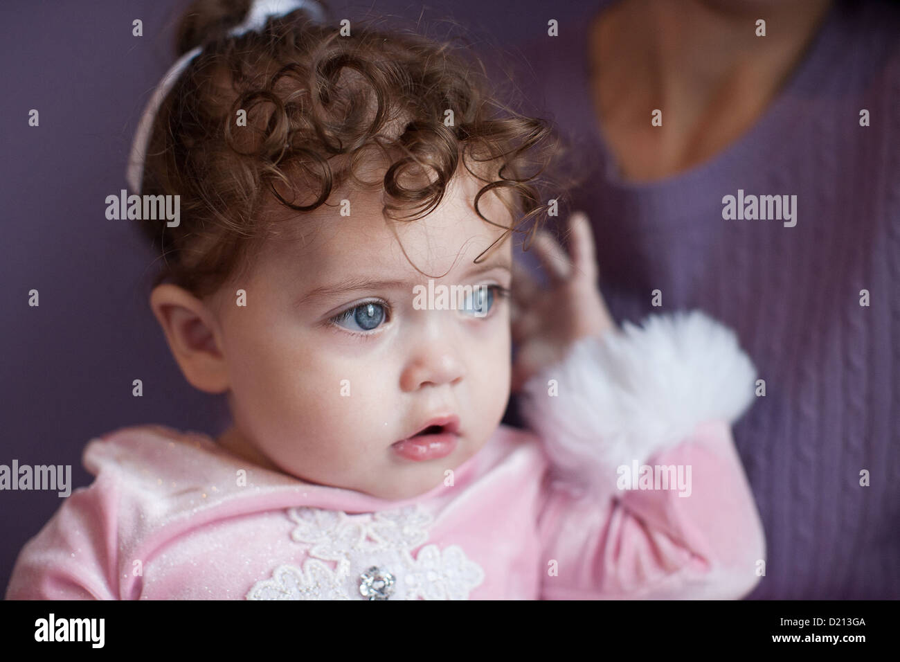 Beautiful one year old girl with bright blue eyes and curly brown hair  looking out a window Stock Photo - Alamy