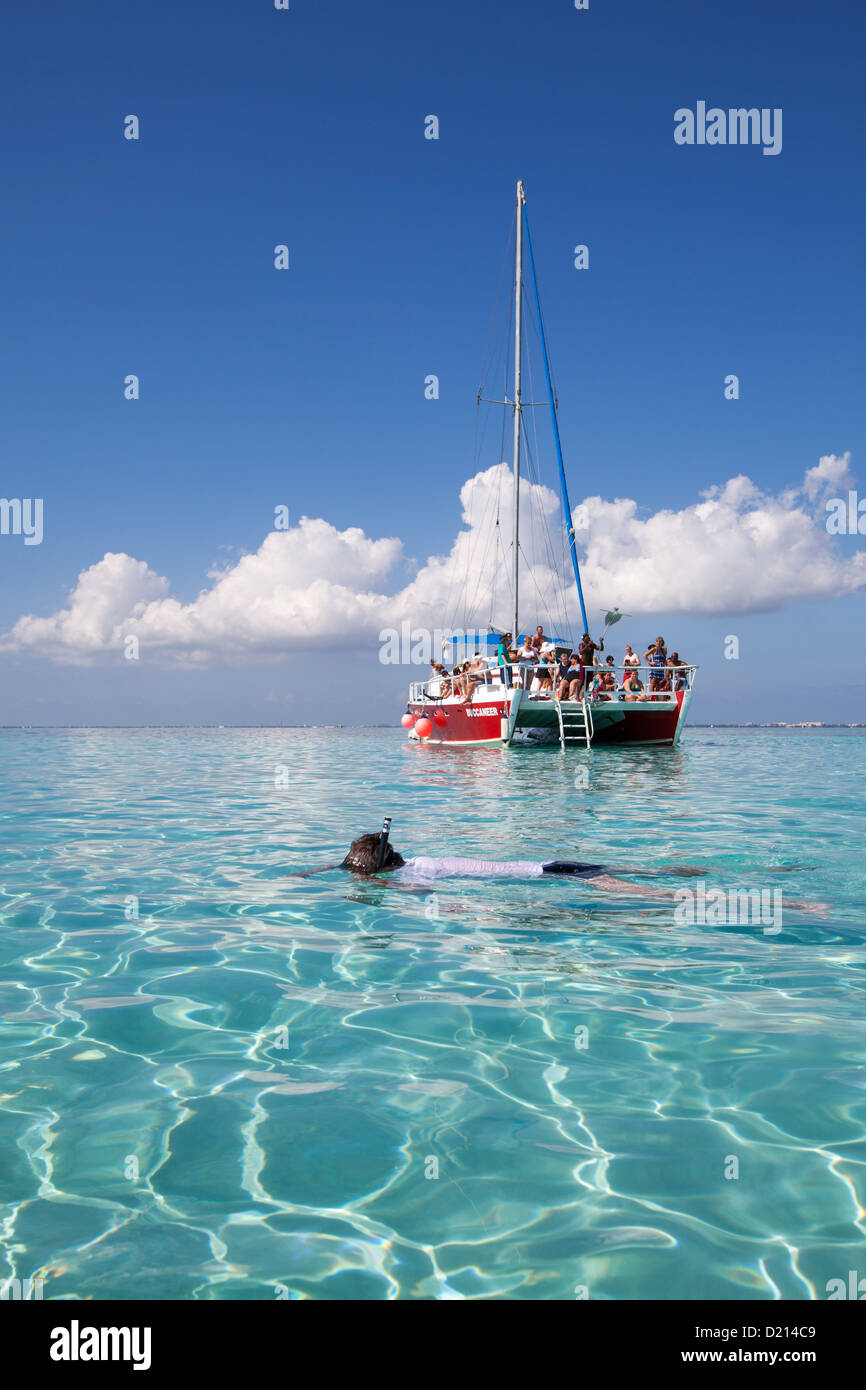 Snorkeler and catamaran sailboat at Stingray City sand bank, Grand