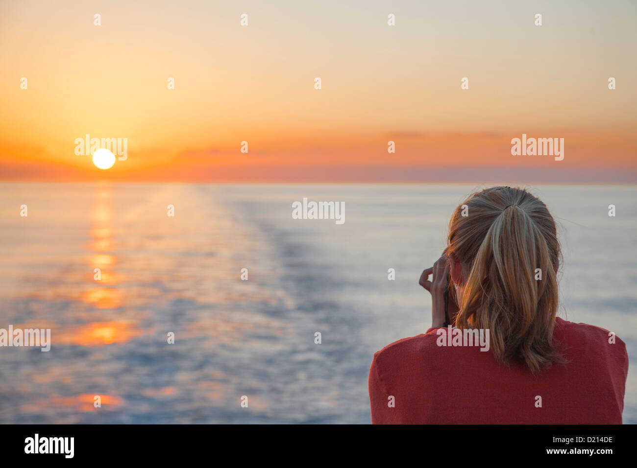 Young woman taking photographs of the sunset from cruise ship MS Deutschland (Reederei Peter Deilmann), Caribbean Sea, near Caym Stock Photo