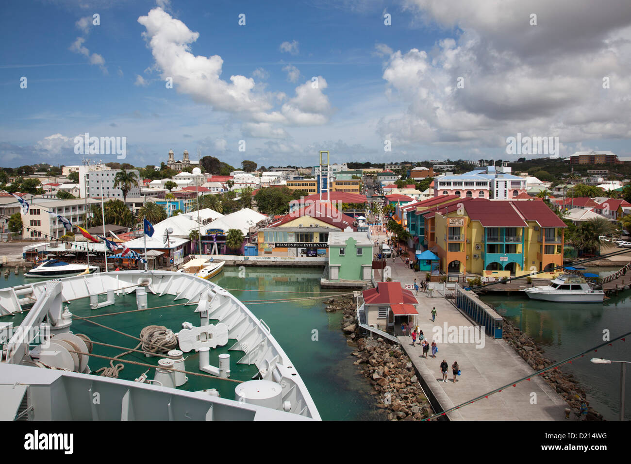 Bow of cruise ship MS Deutschland (Reederei Peter Deilmann) at a pier with colorful houses and shops near the port, St. John's, Stock Photo