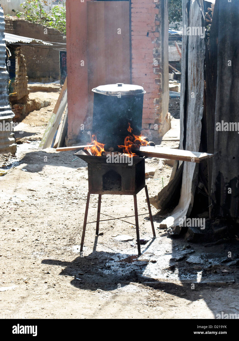 wood fire burns brightly & smoke rises outside from makeshift cooking stove in courtyard of Oaxaca de Juarez building Mexico Stock Photo