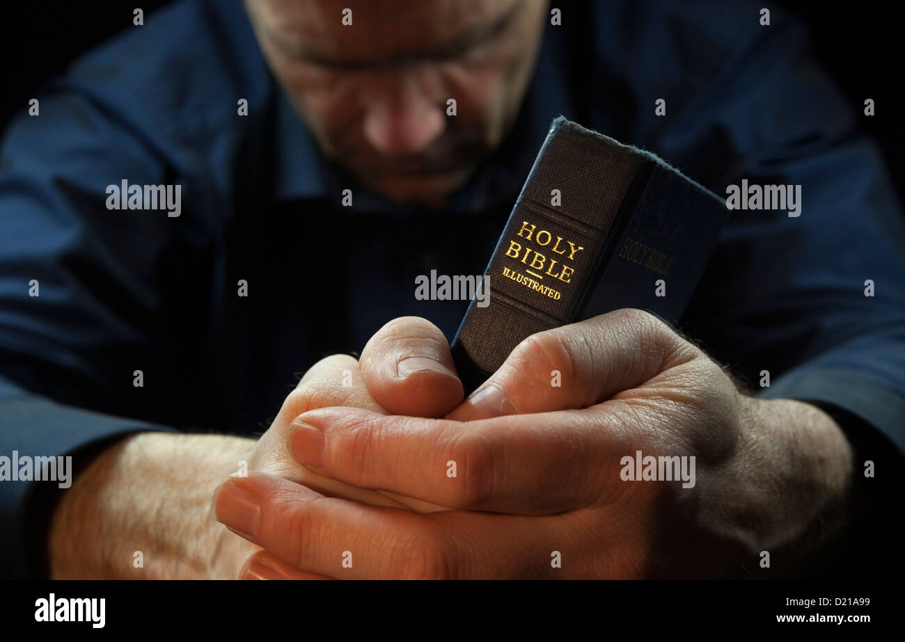 Colour Image of a Man praying holding a Holy Bible. Stock Photo