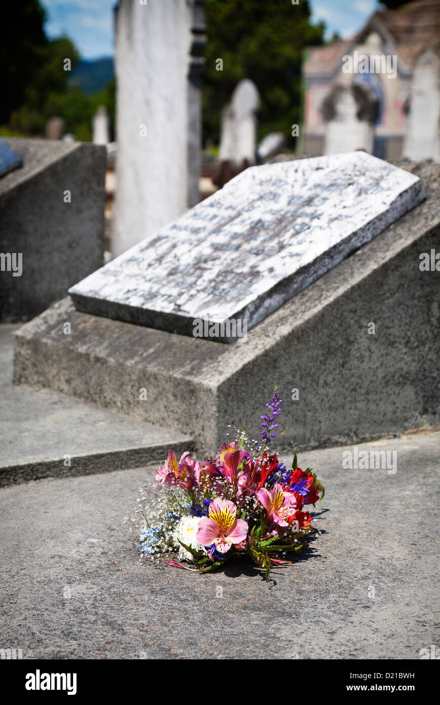 A posy of fresh flowers by an old gravestone. Linwood cemetery, Christchurch, Canterbury, South Island, New Zealand. Stock Photo