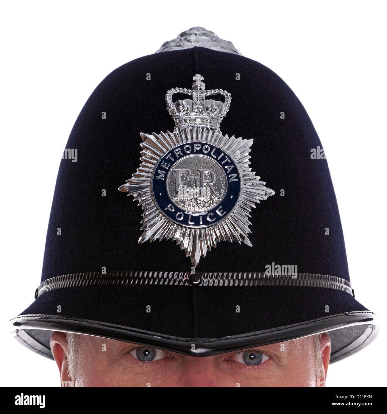 Close up of a British Police officer wearing the traditional helmet with his eyes watching you, studio shot. Stock Photo