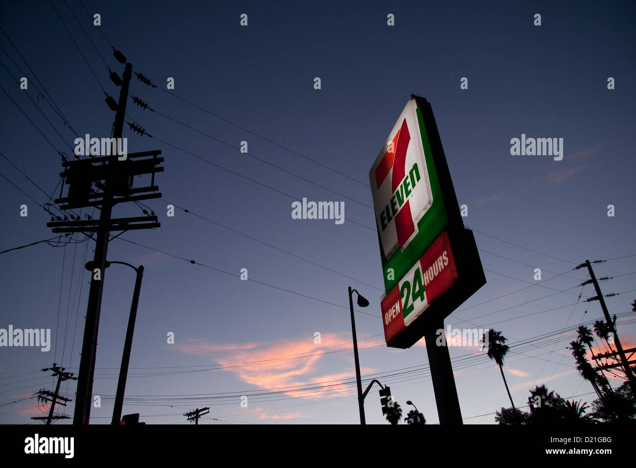7-11 Convenient Store Sign, Telephone poles against sunset sky Stock Photo