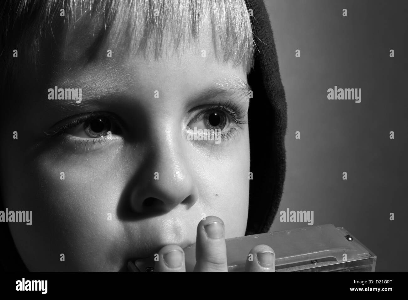 black and white photo of boy in the hood playing the harmonica Stock Photo