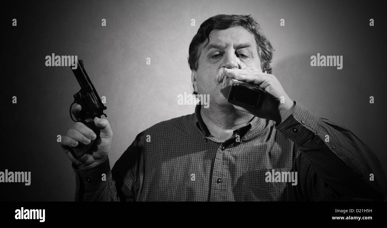 man holding a gun in his hand and drank from a bottle of whiskey Stock Photo
