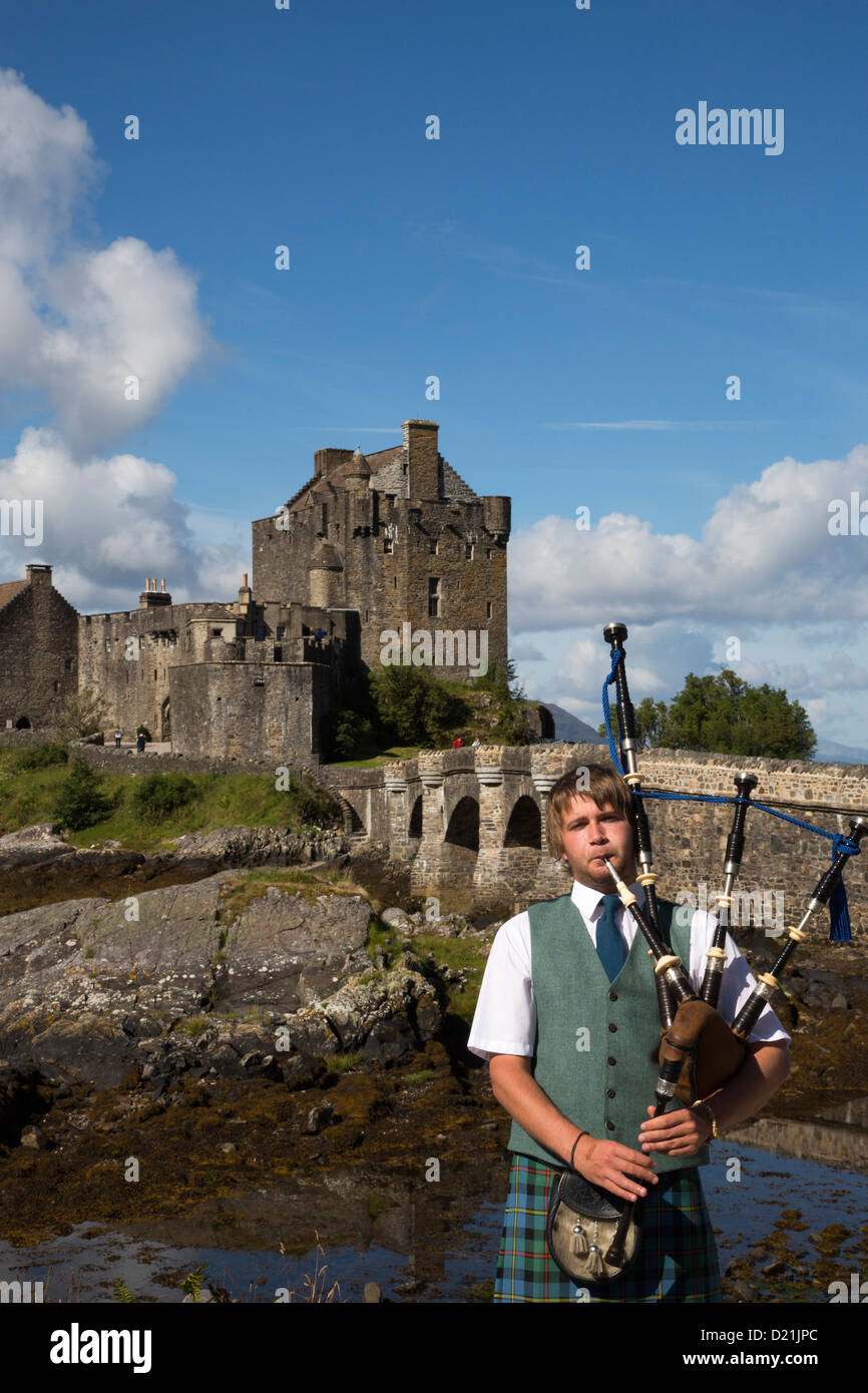 Young bagpiper in front of Eilean Donan Castle at Loch Duich, Near Dornie, Highland, Scotland, United Kingdom Stock Photo