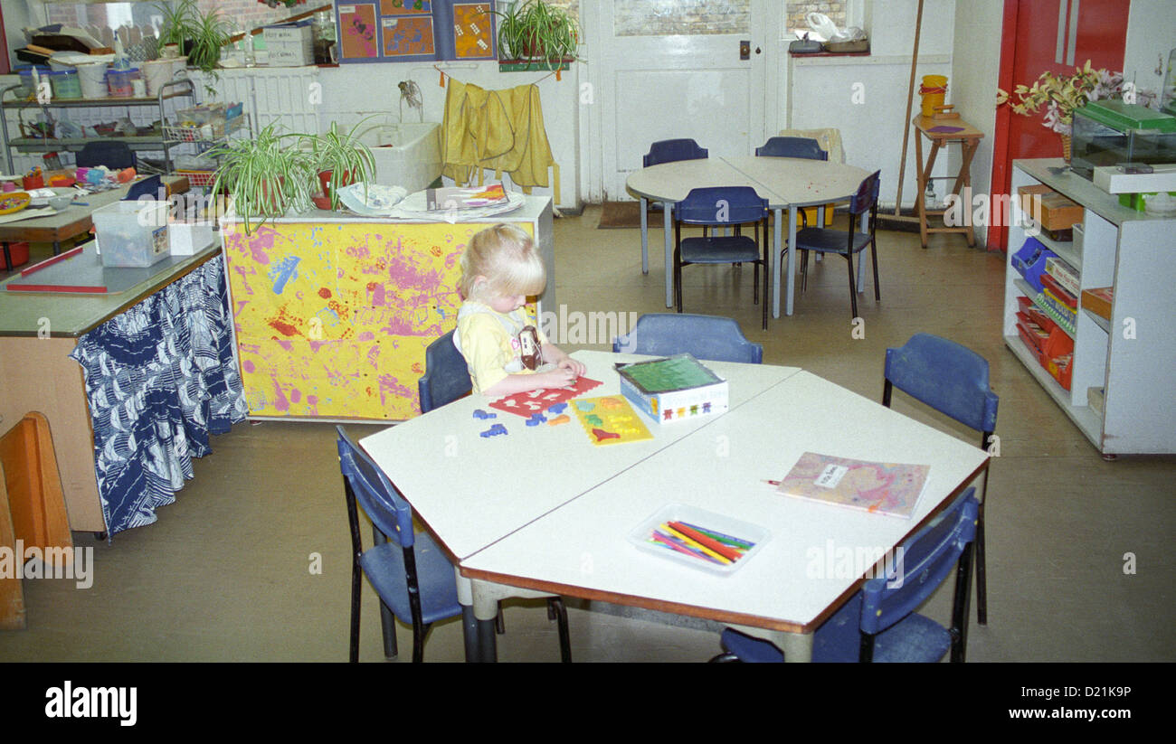 Deaf nursery class child alone seated at table UK Stock Photo