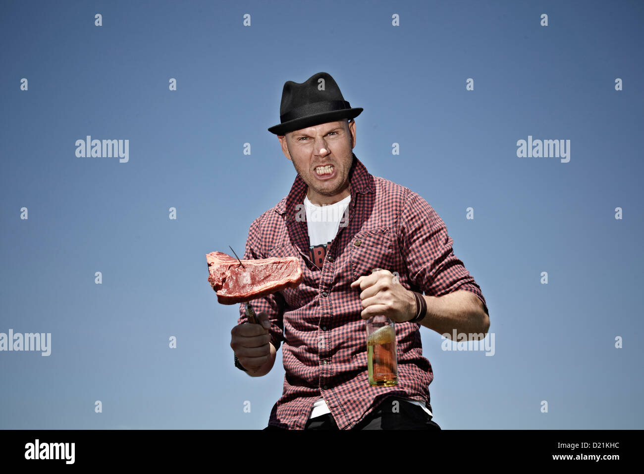 Germany, Cologne, Mature man with meat and beer Stock Photo