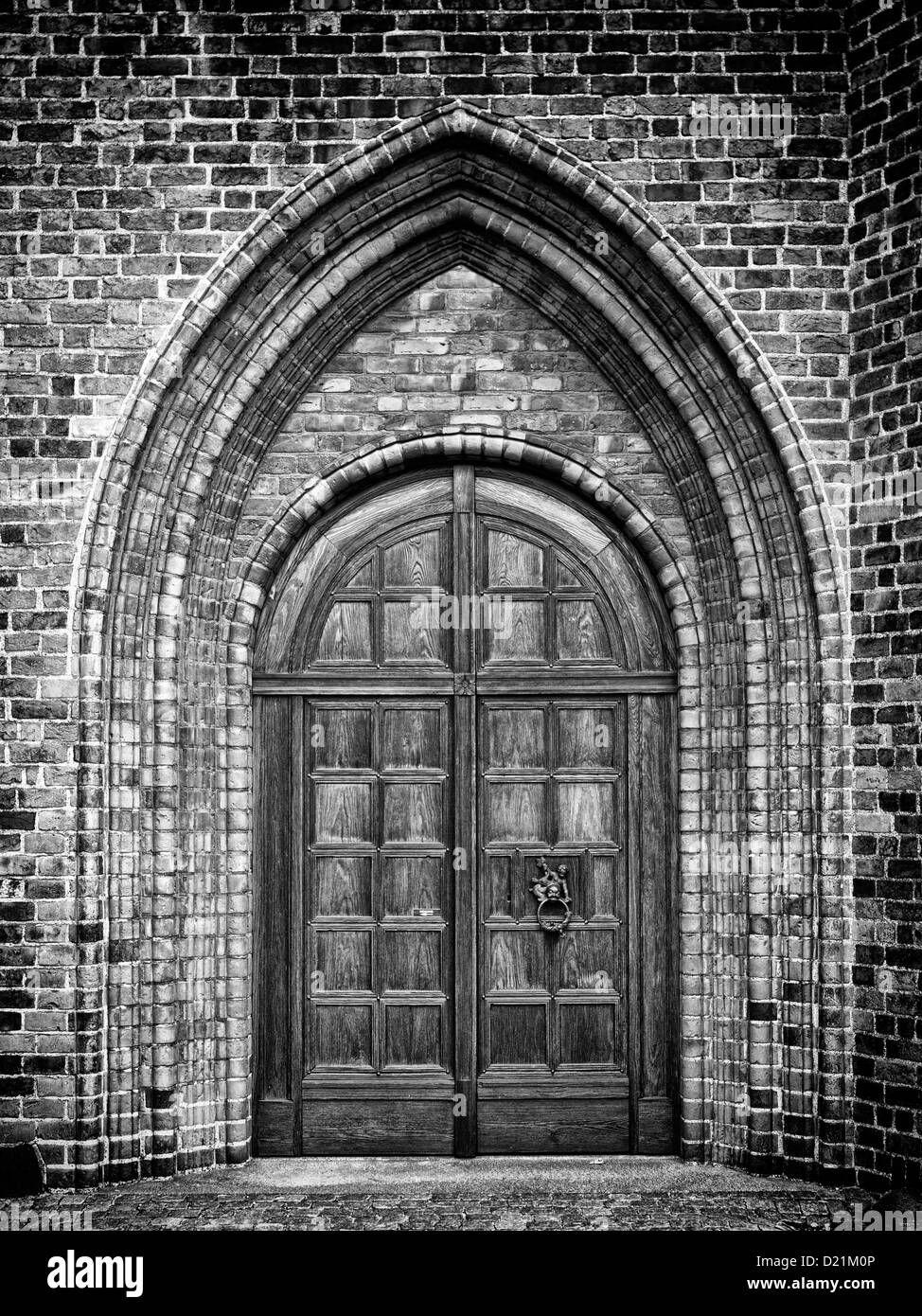 A black and white photo of an arched doorway to a gothic style church. Stock Photo