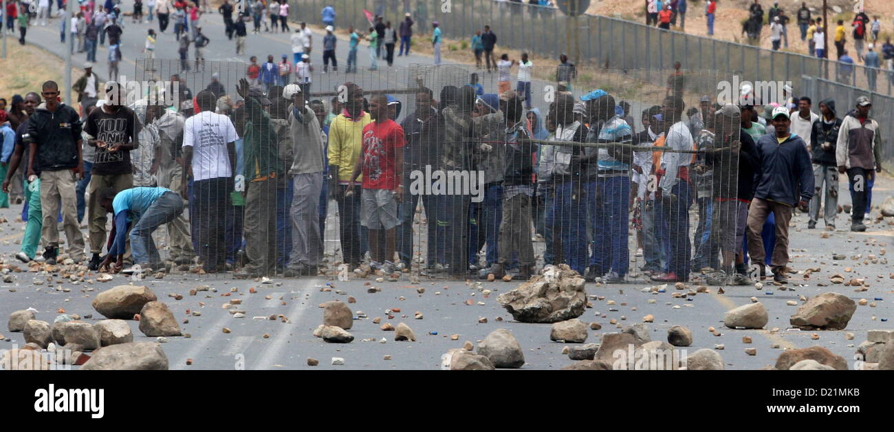GRABOUW, SOUTH AFRICA: Striking Farm workers stand behind fencing as Police fight to hold them off from making barricades to block off the N2 on January 10, 2013 in Grabouw, South Africa. Seasonal farm workers are striking over wage disputes.  (Photo by Gallo Images / Nardus Engelbrecht) Stock Photo