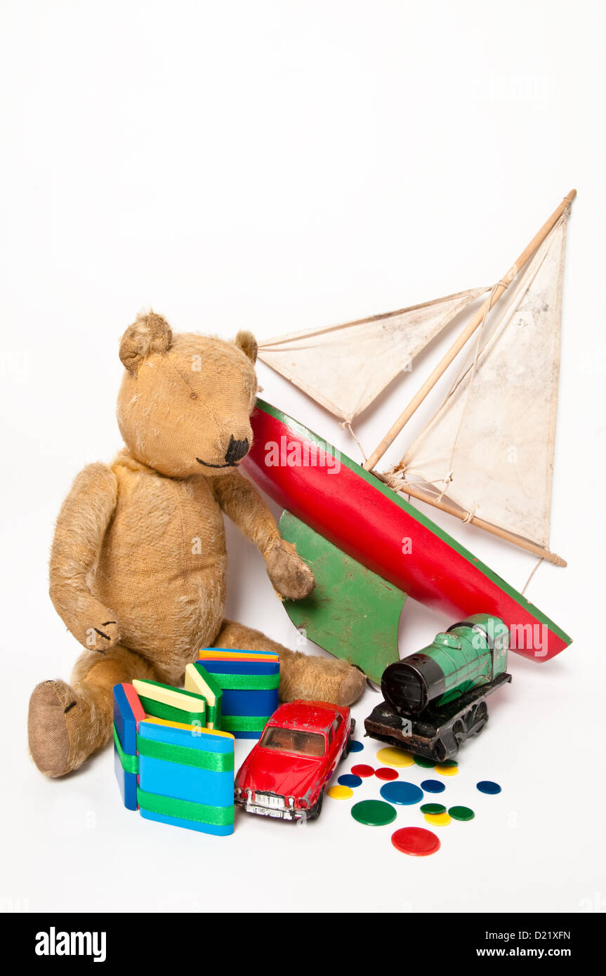 A collection of well-loved classic simple children's toys including a cute teddy bear, red wooden sailing boat, and green train Stock Photo