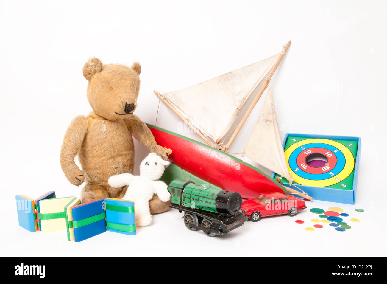 A collection of well-loved classic simple children's toys including a cute teddy bear, red wooden sailing boat, and  green train Stock Photo