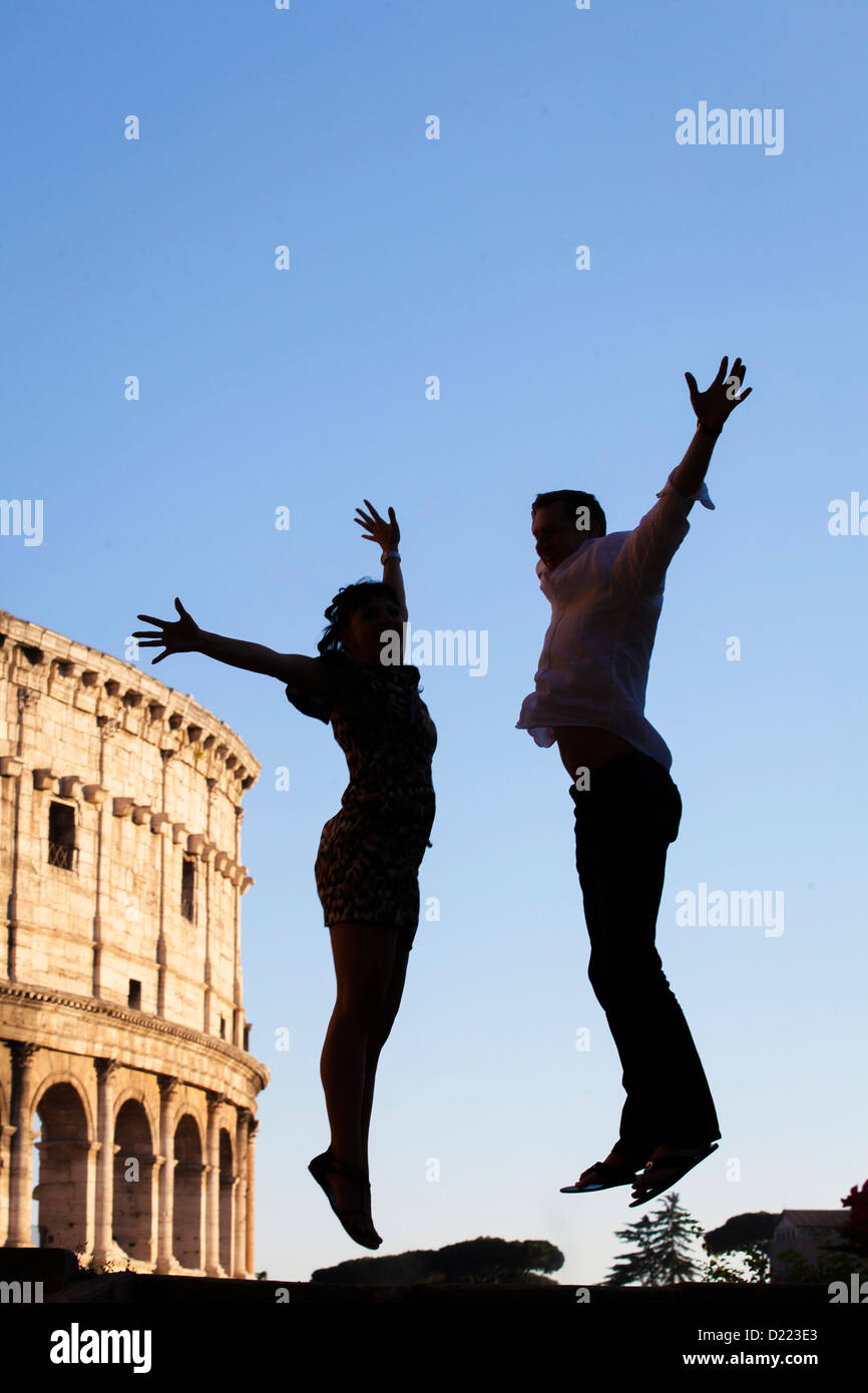 Couple jumping for joy at the roman Colosseum in Rome Italy Stock Photo